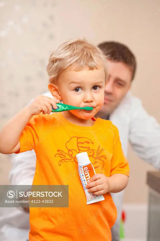 Father learning his child how to brush teeth.