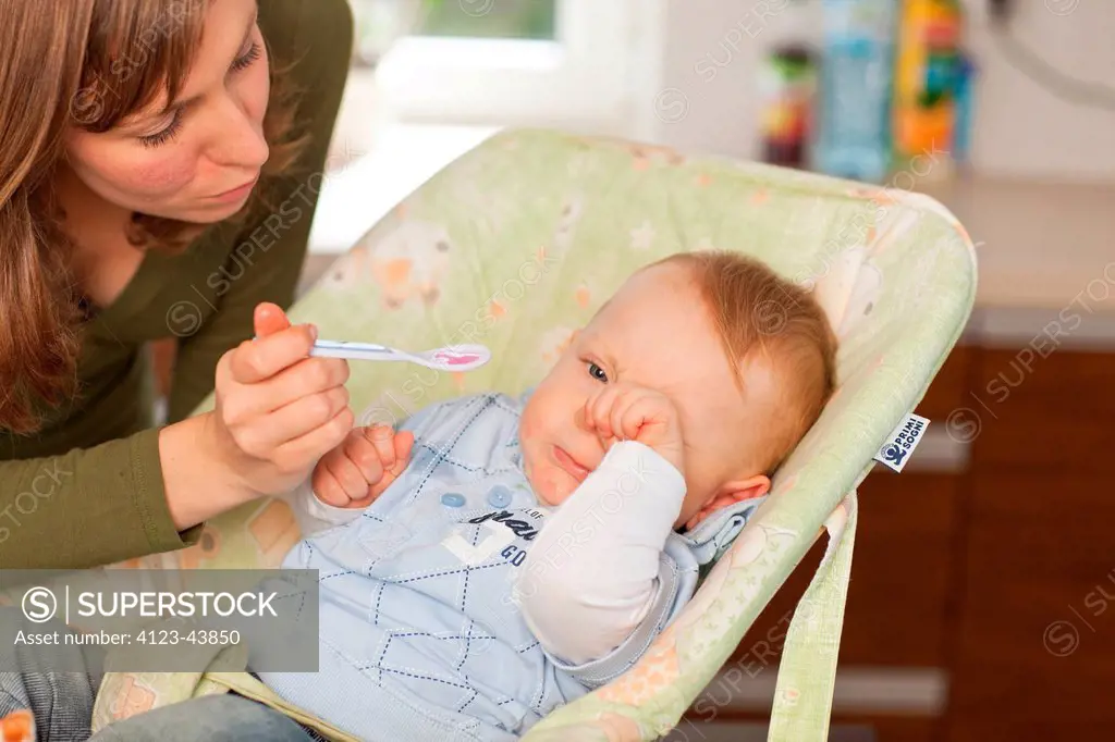 Mother dosing up her baby with a syrup.