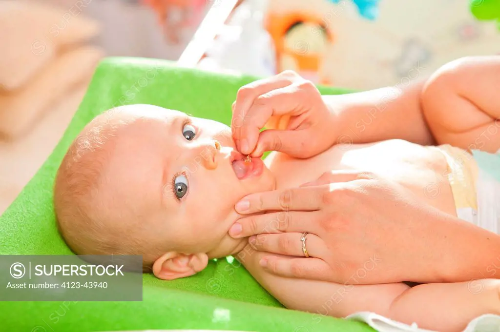 A baby being given a pill.