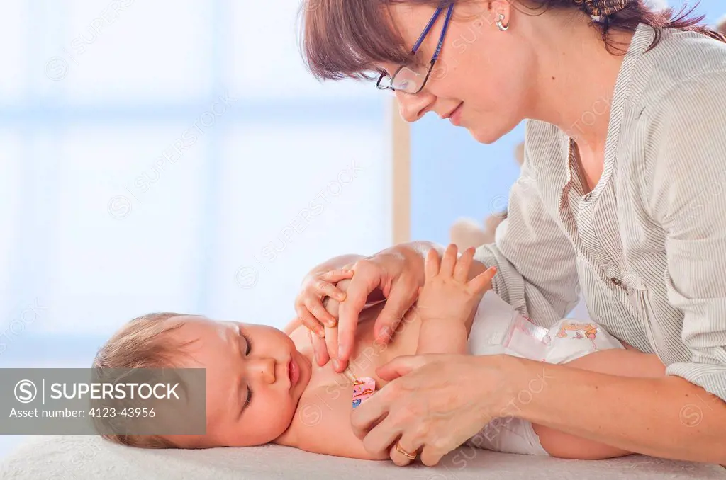 Mother putting sticking plaster on her baby's arm.
