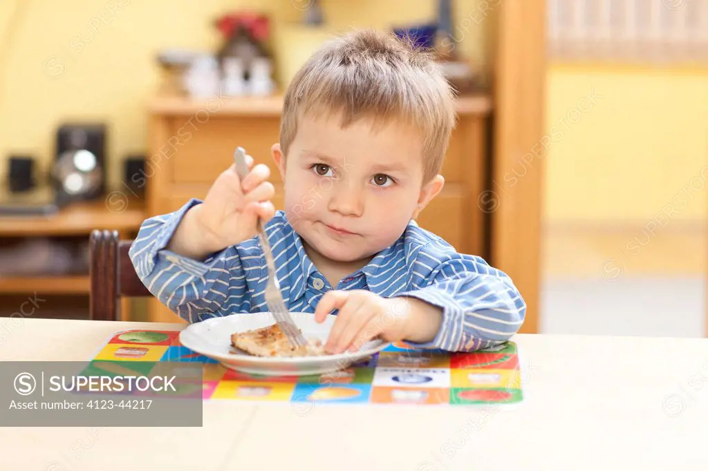 Little boy sitting at dinner table.