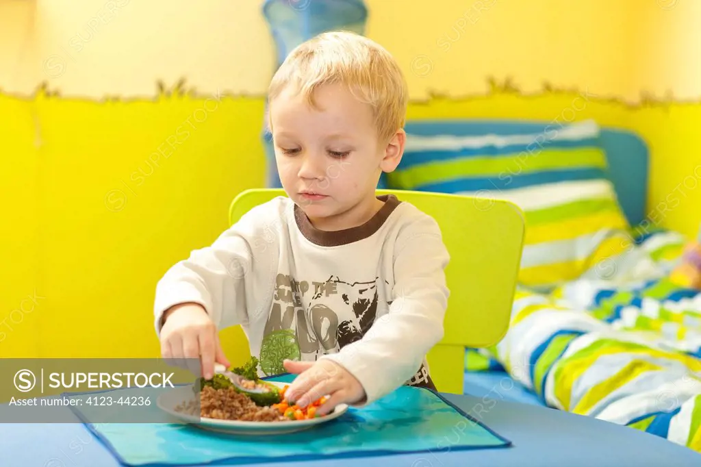 Little boy eating at table in his room.
