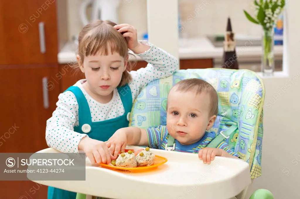 Girl feeding her younger brother.
