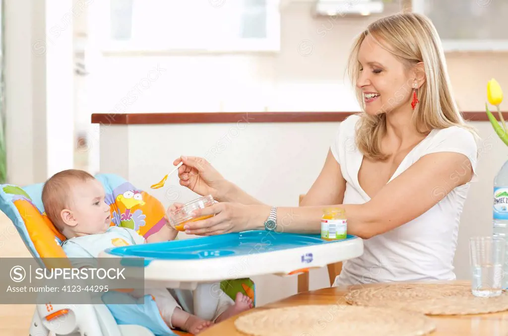 Young mother feeding her baby with soup.