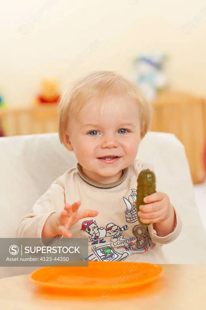 Adorable baby boy eating pickled cucumber.