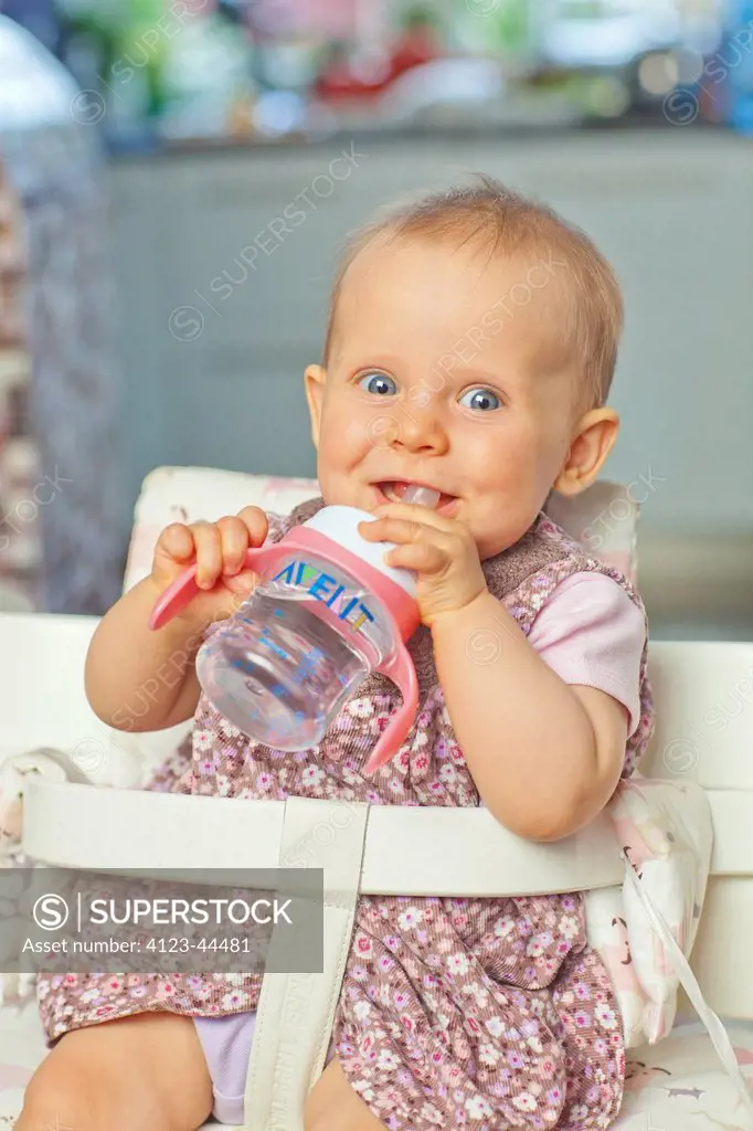 Cute little girl drinking water from cup.
