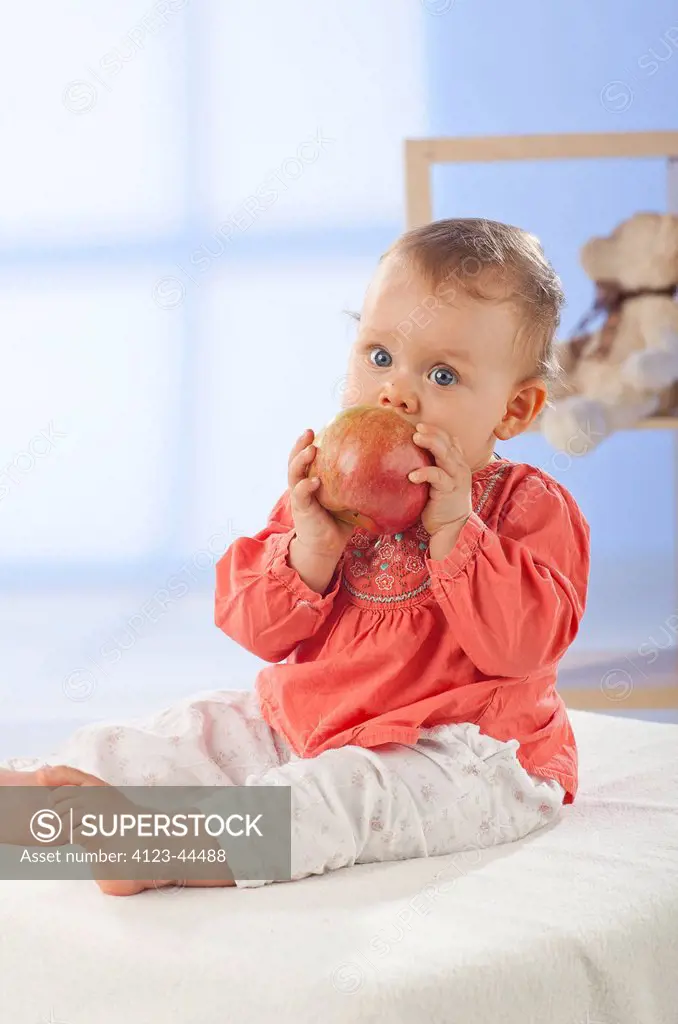 Adorable baby girl eating apple.