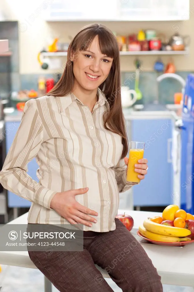 Young woman drinking fresh juice, enjoying her pregnancy.