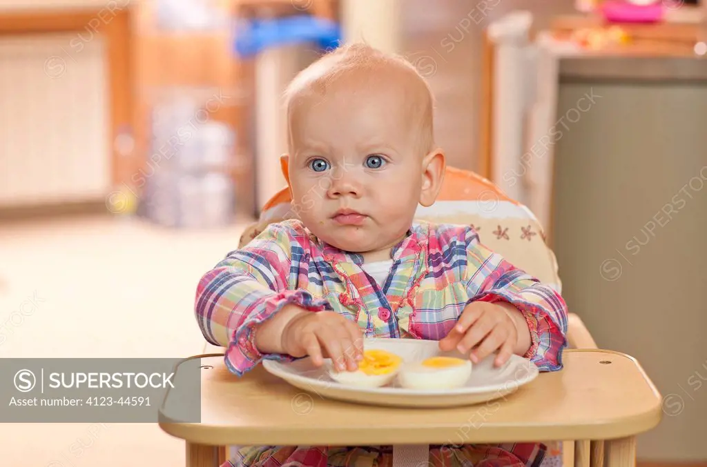 Adorable baby girl eating boiled eggs.