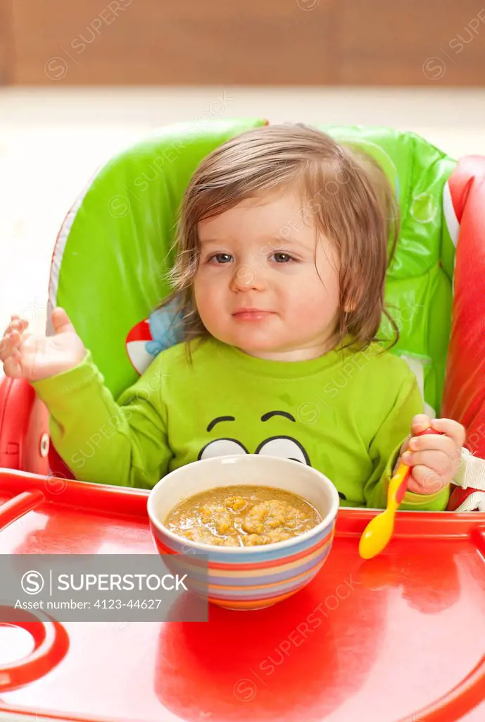 Girl eating in baby chair.