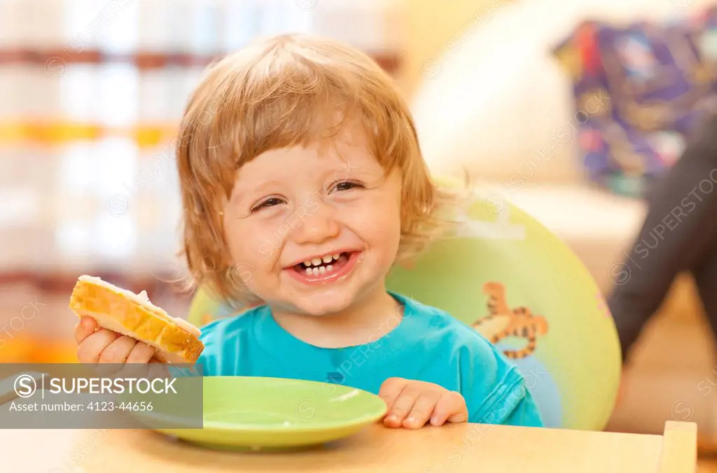Adorable red-haired girl eating lunch at a baby table.