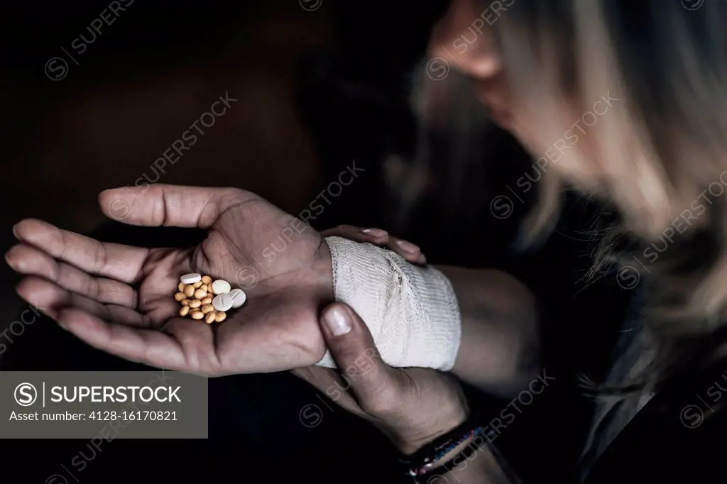 Suicidal woman holding number of pills in hand.