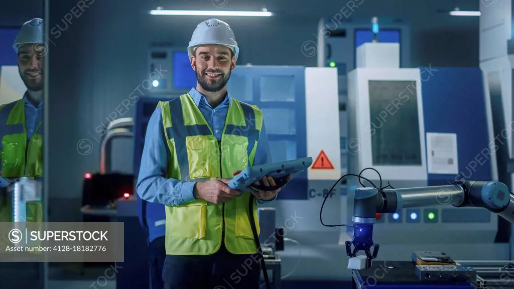 Engineer using digital tablet to manipulate robot arm