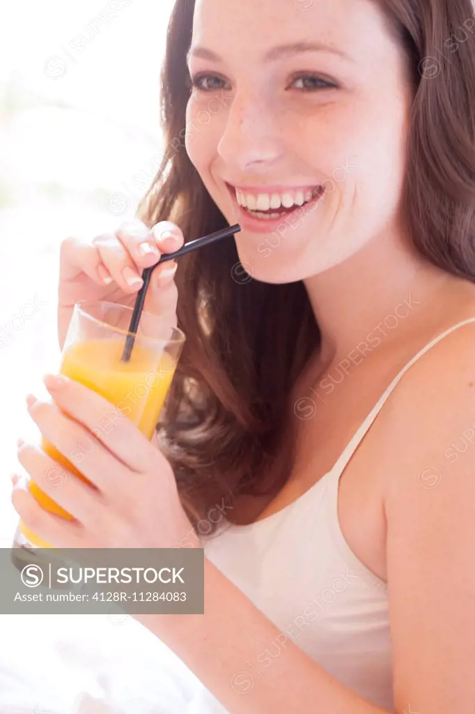 MODEL RELEASED. Young woman drinking fruit juice.