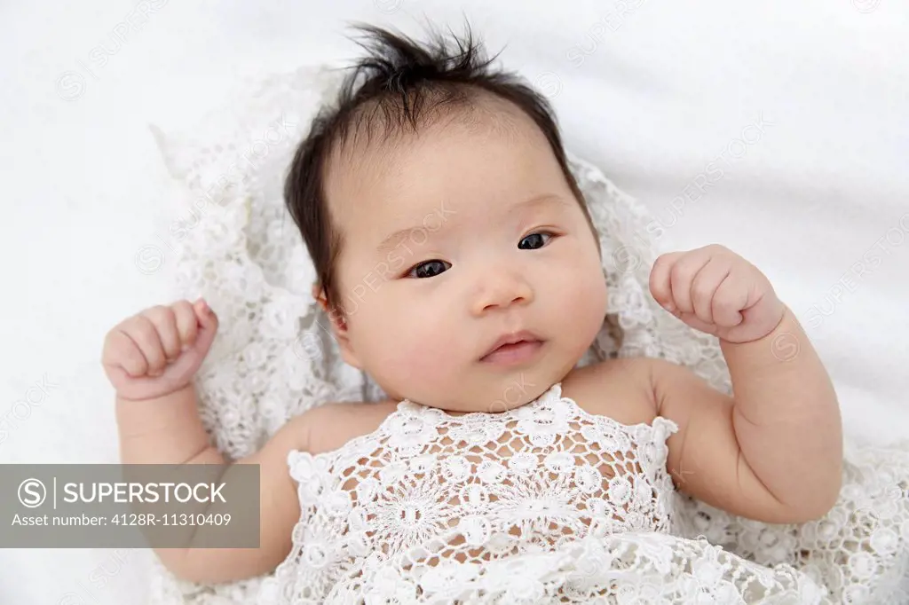 MODEL RELEASED. Baby girl lying down with hand clenched, portrait.