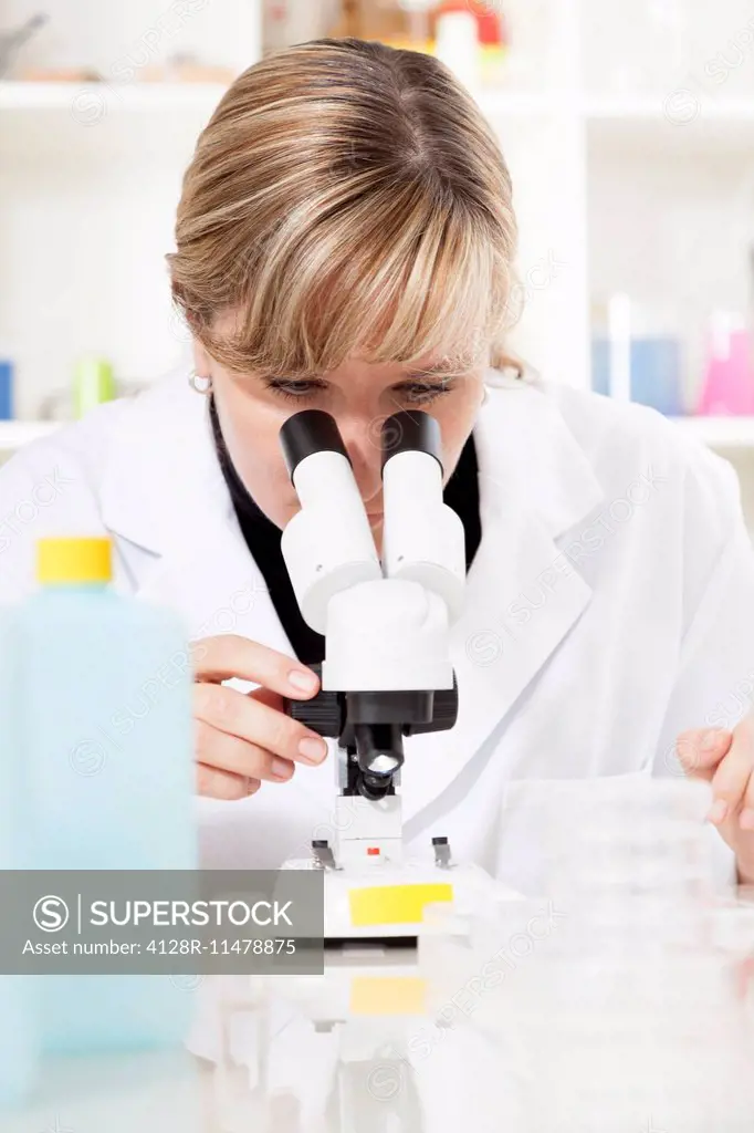 MODEL RELEASED. Female laboratory technician using a microscope.