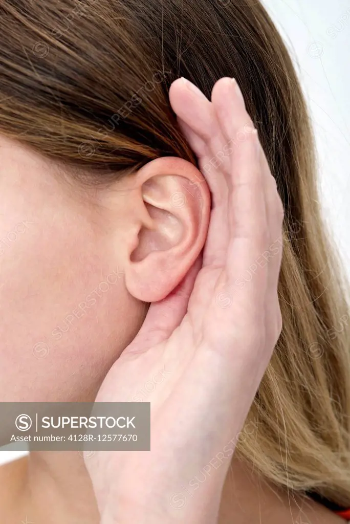 Young woman with hand cupping ear.