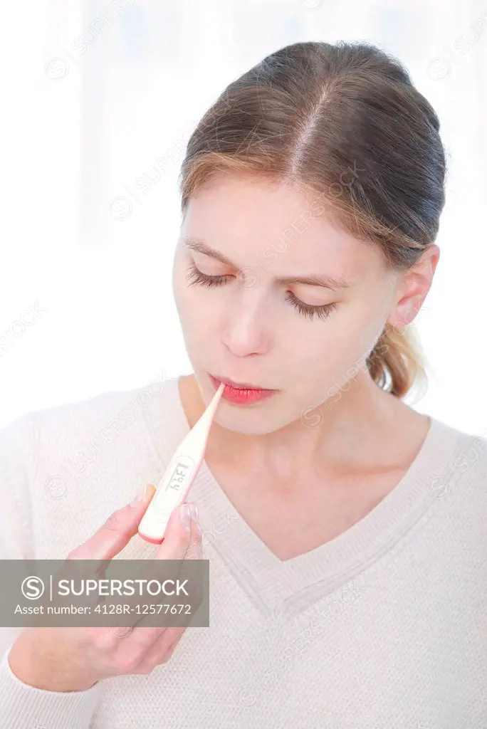 Young woman taking her temperature.