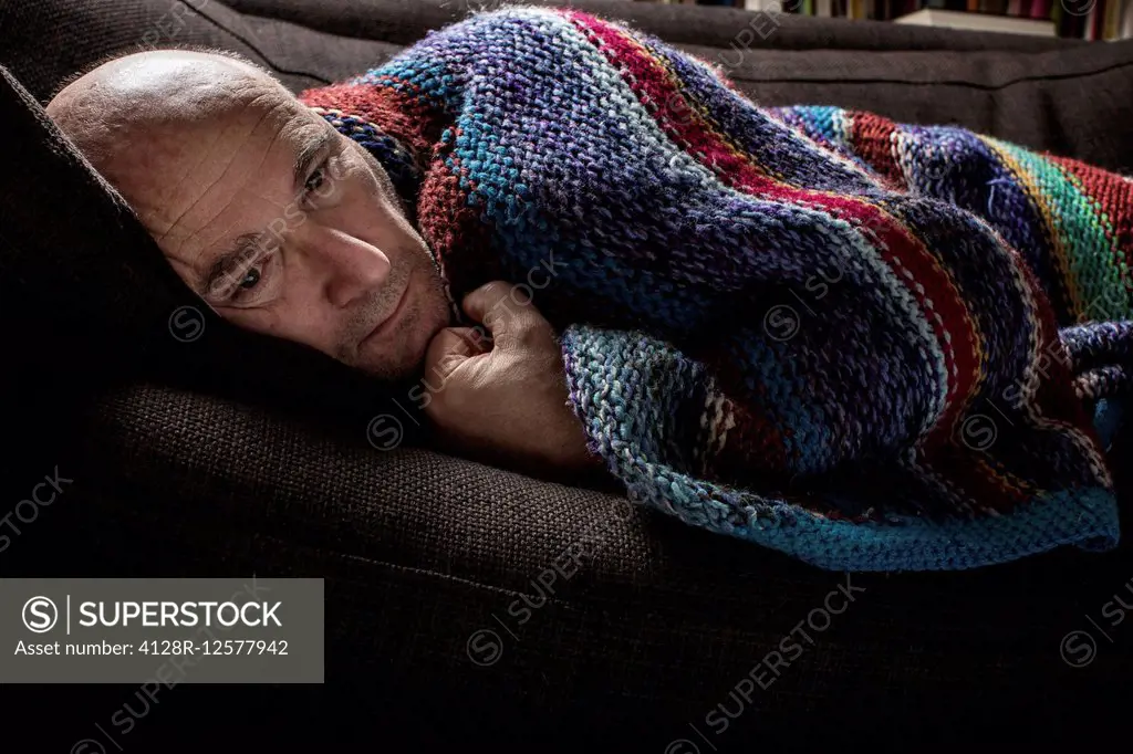 Mature man wrapped in a blanket.
