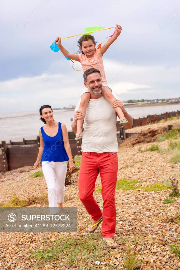 Father carrying his daughter on his shoulders on the beach.