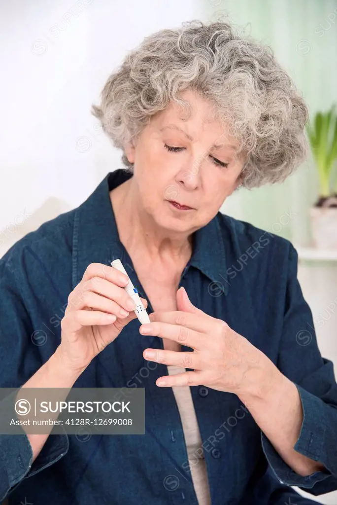 MODEL RELEASED. Senior woman using a finger prick test to test her blood.