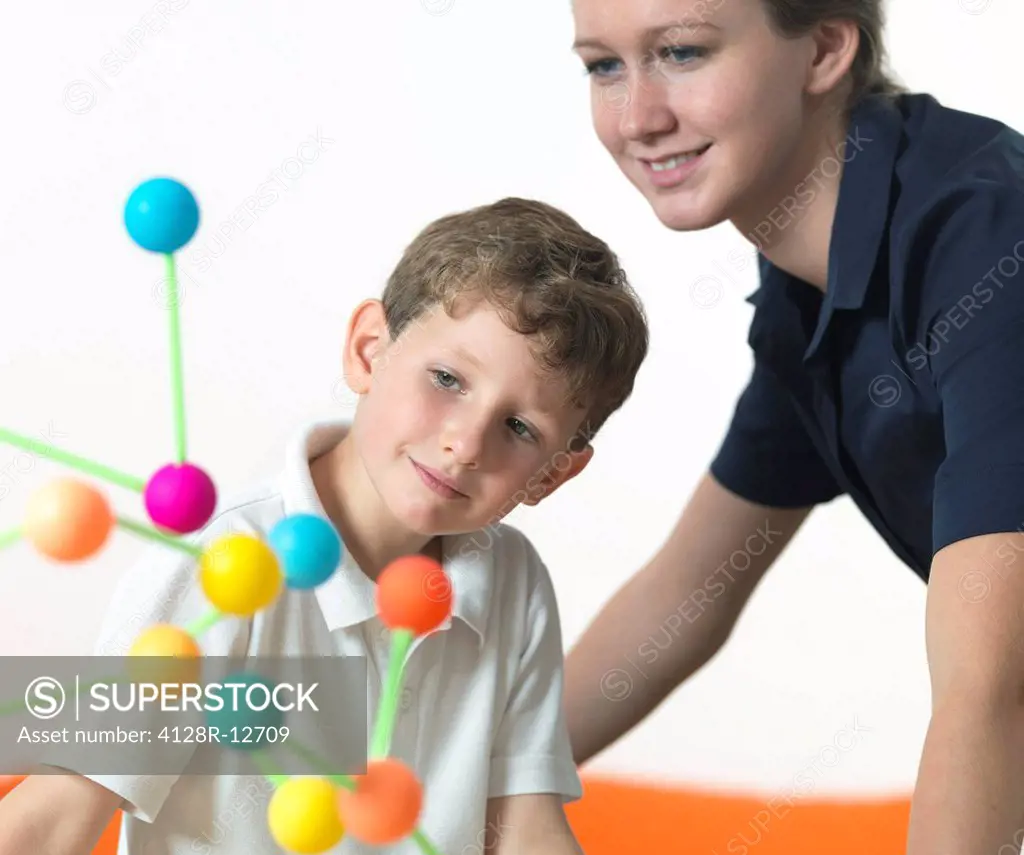 Chemistry lesson. 6 year old boy and his teacher looking at a molecular structure.