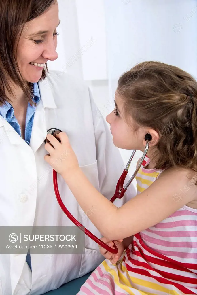Girl using a stethoscope on doctor
