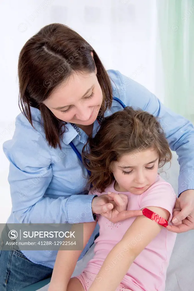 Woman applying plaster to girl's arm