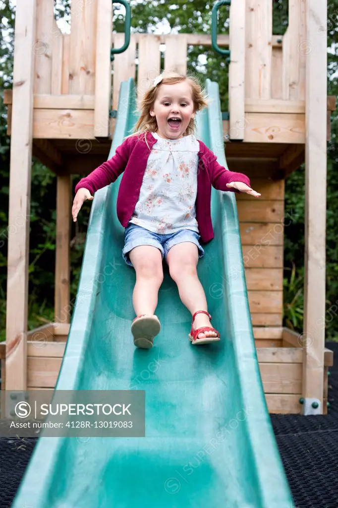 MODEL RELEASED. Girl sliding down a slide.