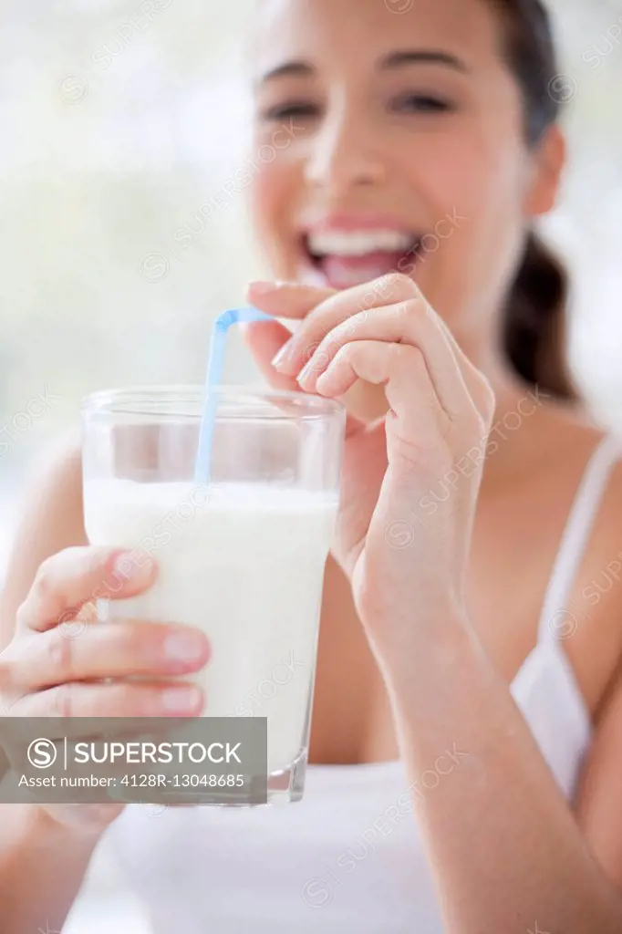 MODEL RELEASED. Woman with a glass of milk and a drinking straw.