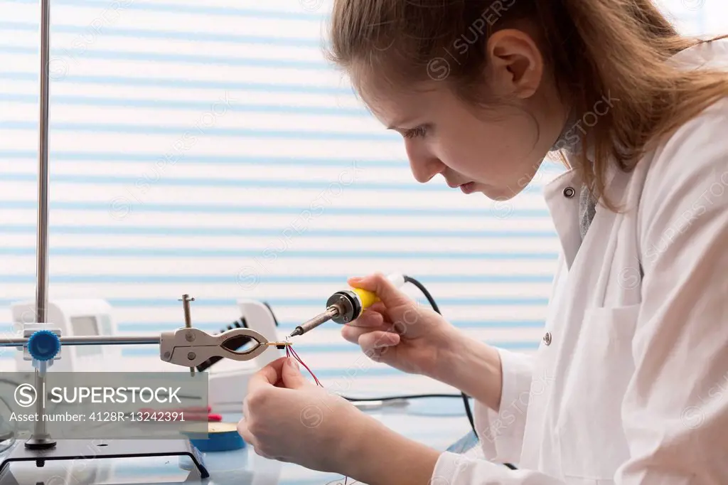 Female technician soldering wires in the laboratory.