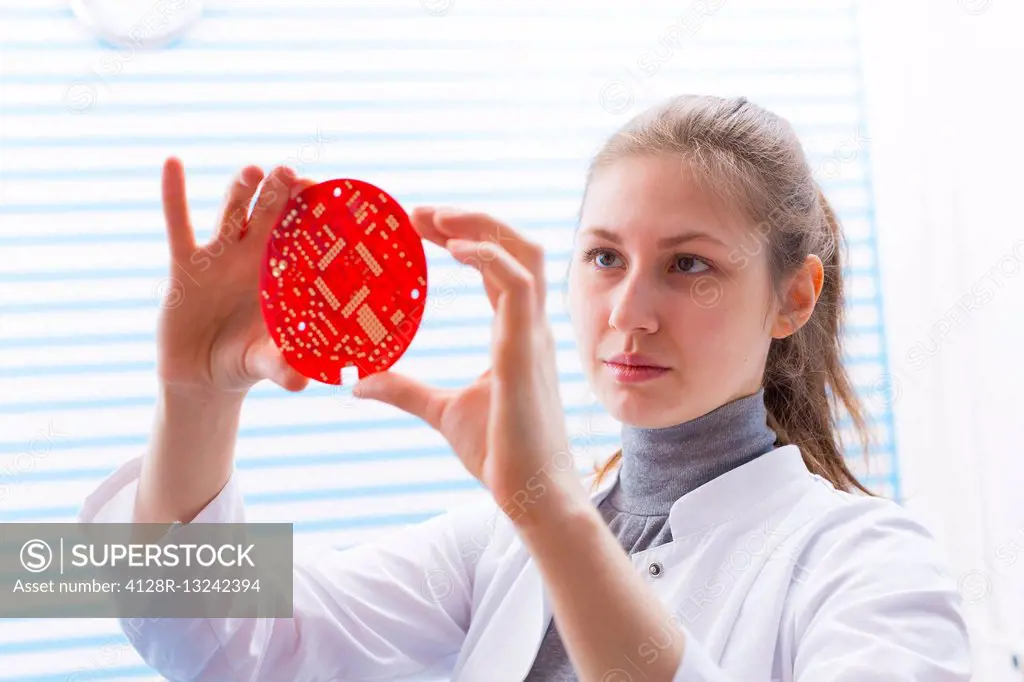 Female technician holding electrical component in the laboratory.
