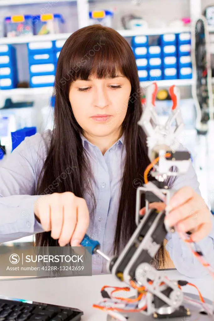 Female electrical engineer working on a robotic arm.