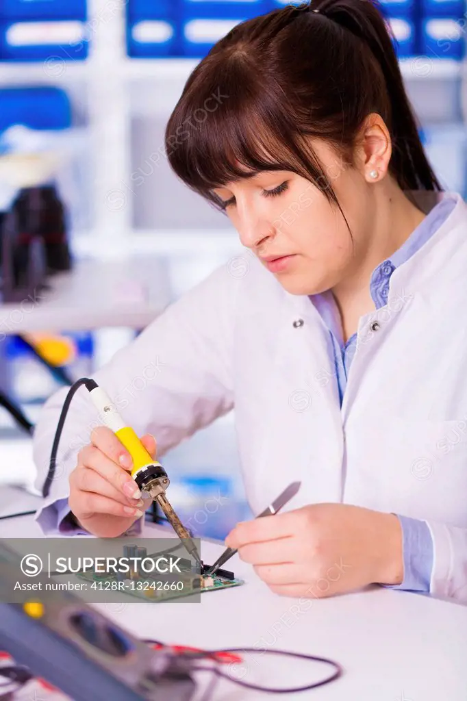 Female electrical engineer testing a circuit board.
