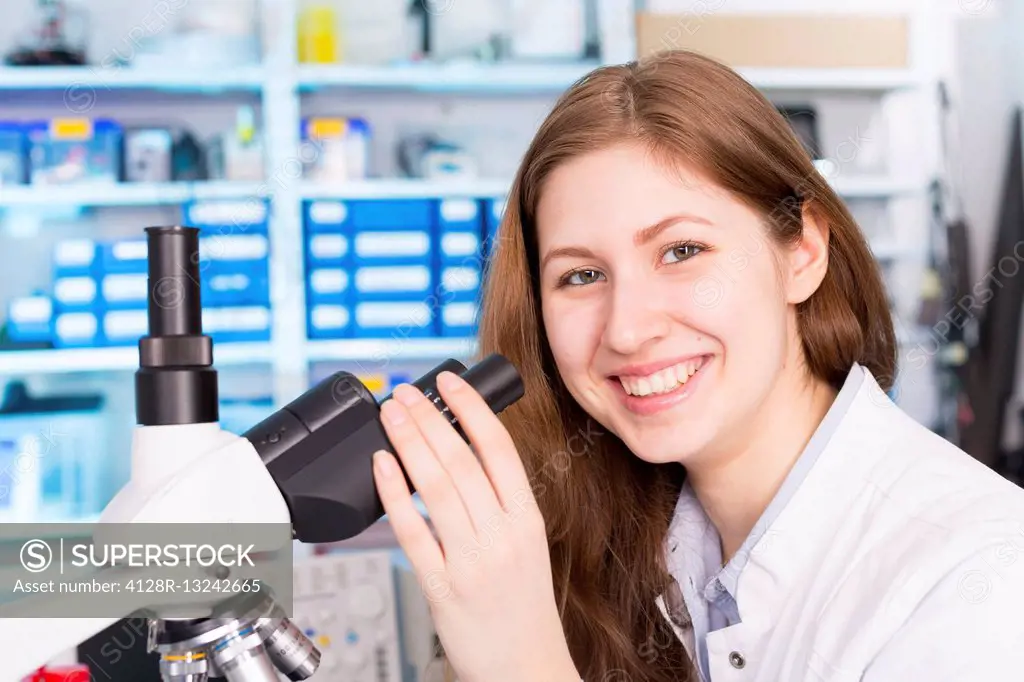 Female lab technician using microscope.