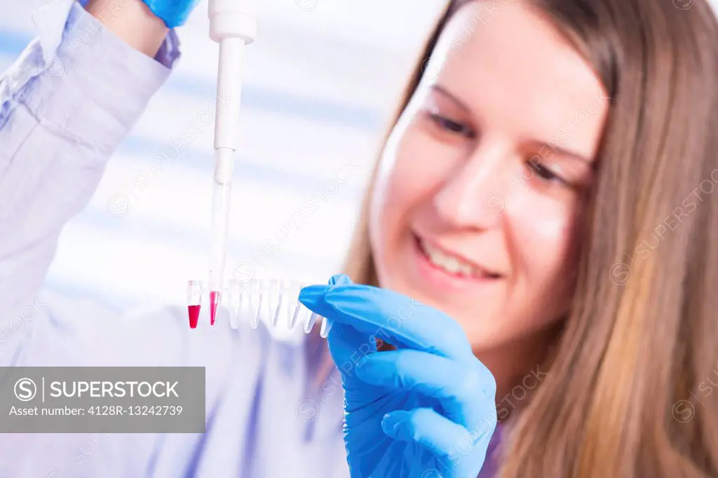 Female lab technician using pipette and micro tubes.