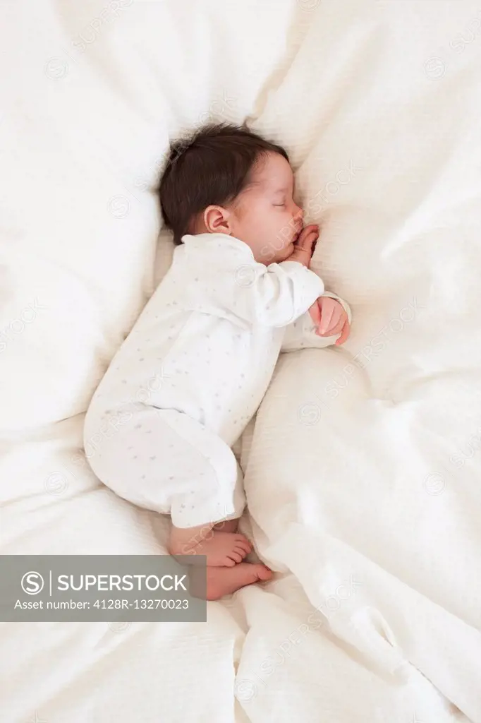 MODEL RELEASED. Newborn baby girl asleep on bed.