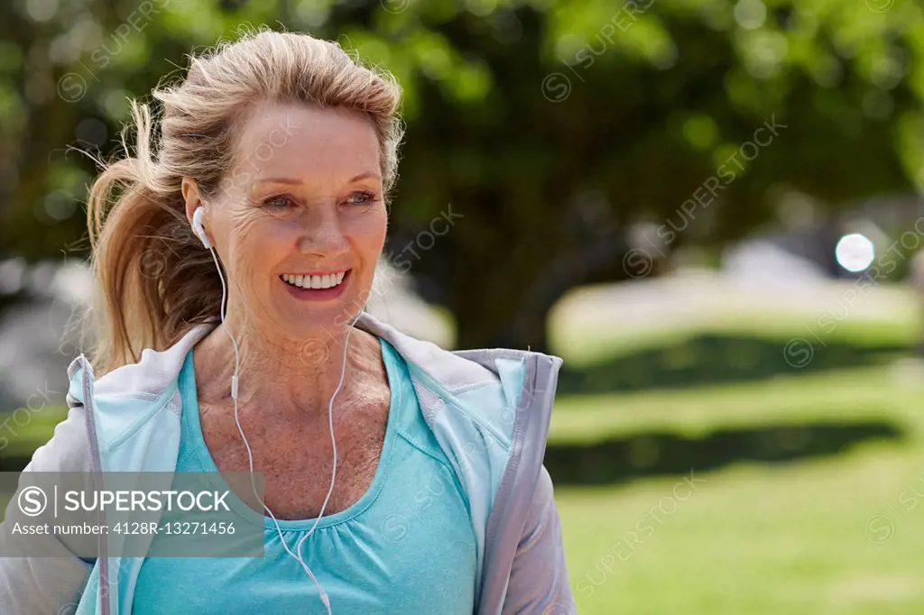 MODEL RELEASED. Senior woman exercising wearing earphones.