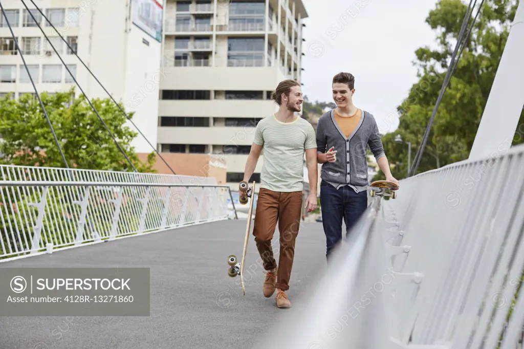 MODEL RELEASED. Two young men walking with skateboards.