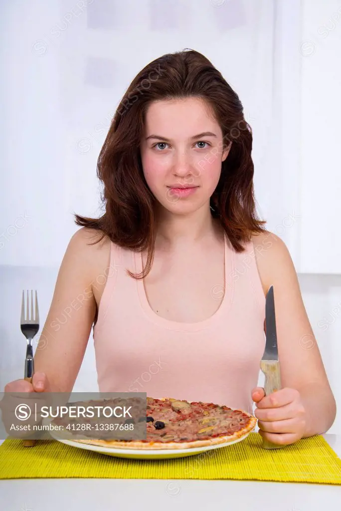 MODEL RELEASED. Teenage girl with a plate of pizza.