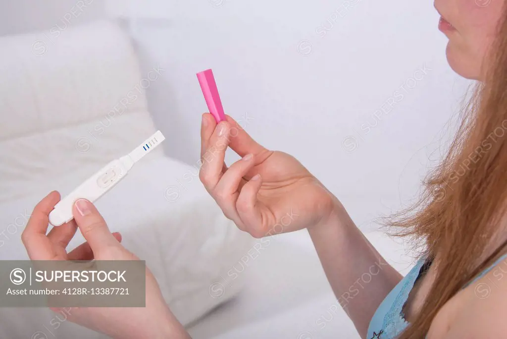 MODEL RELEASED. Young woman taking pregnancy test at home.
