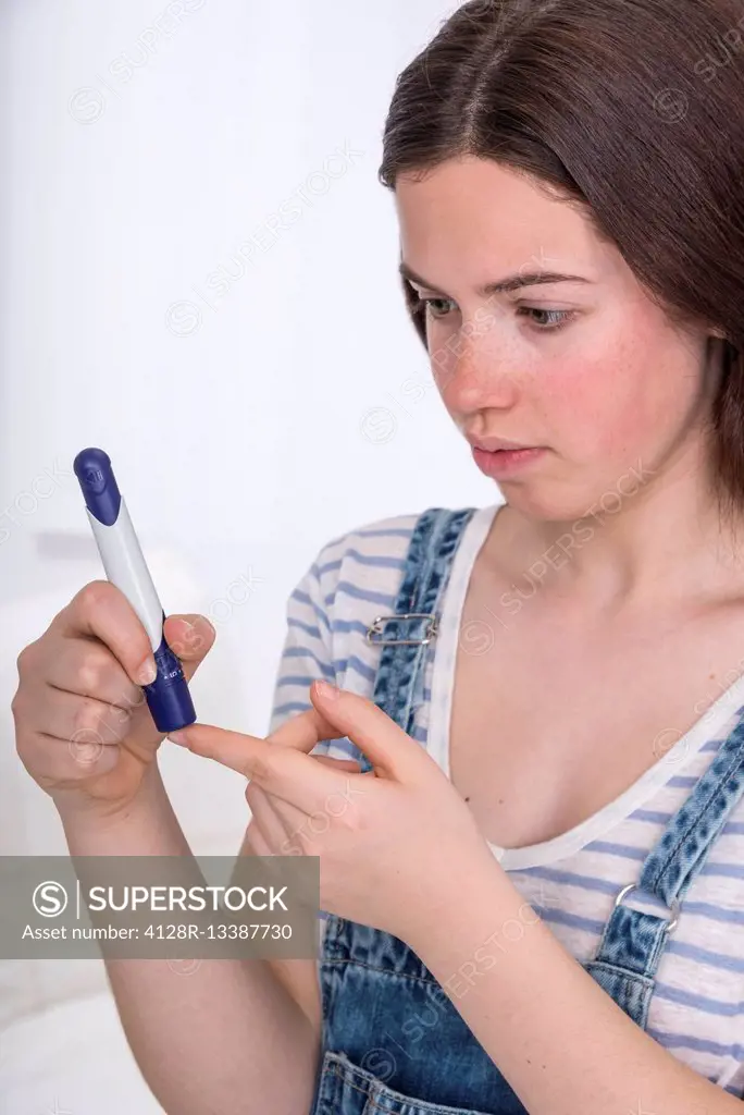 MODEL RELEASED. Teenage girl doing a finger prick test.