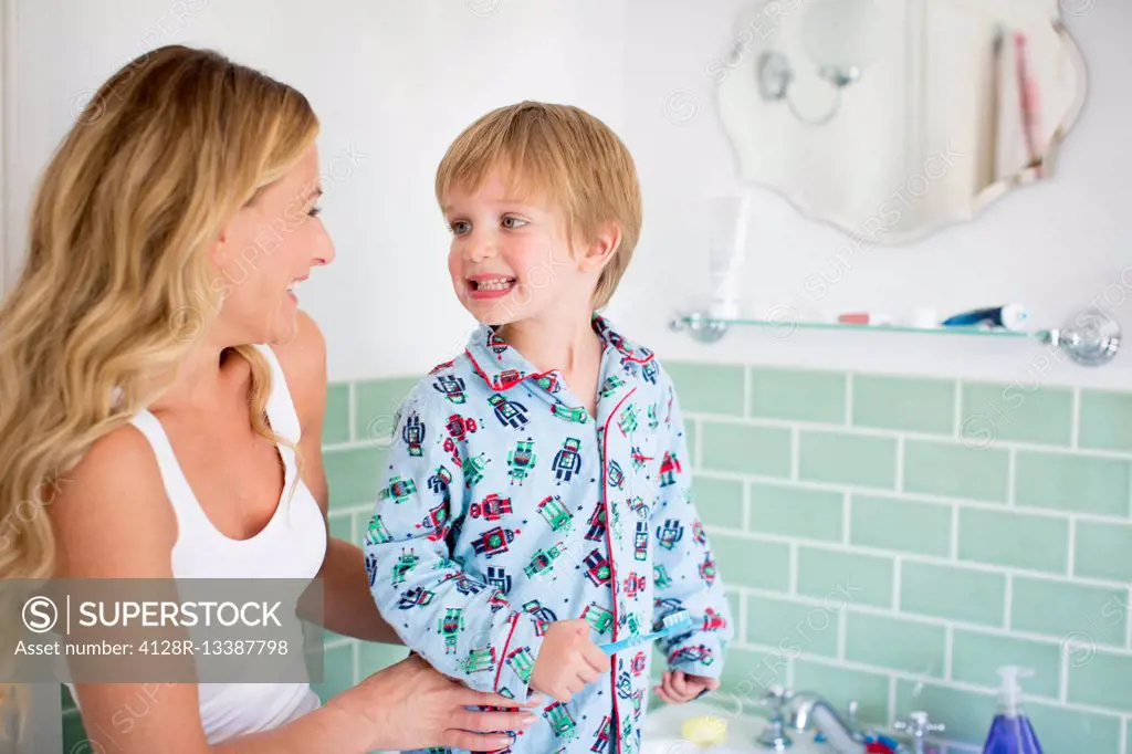 MODEL RELEASED. Mother and son in bathroom brushing teeth.