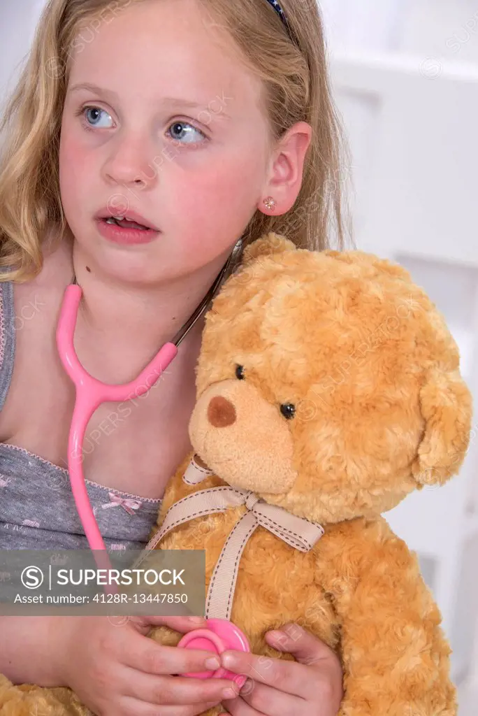 MODEL RELEASED. Girl using stethoscope with teddy bear.
