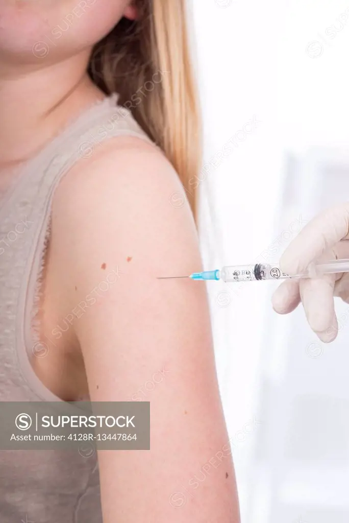 MODEL RELEASED. Teenage girl having injection in arm.