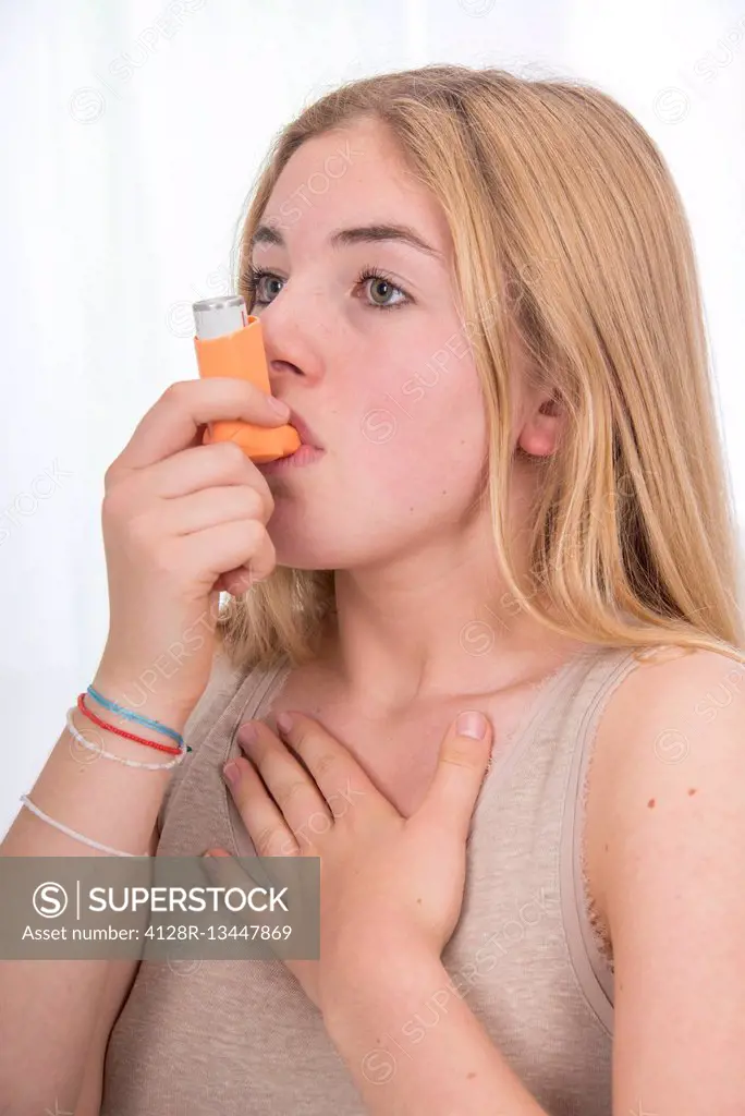 MODEL RELEASED. Teenage girl using inhaler.