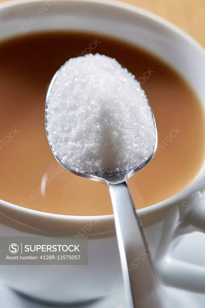 Spoonful of sugar and hot drink, close up.