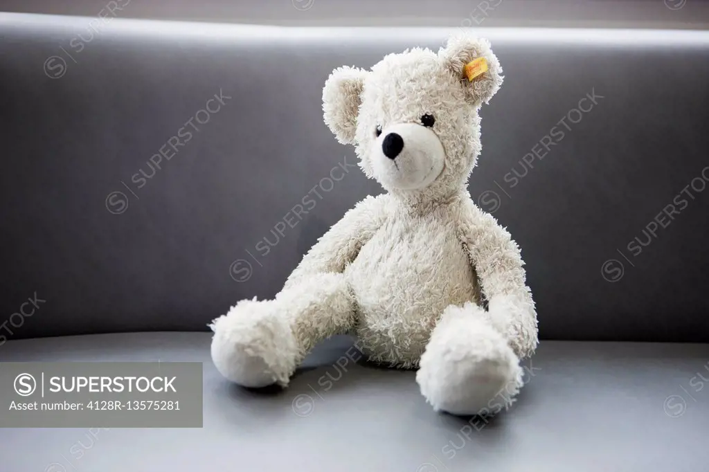 Teddy bear sitting on waiting room seat.