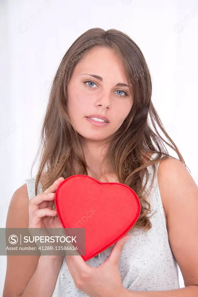 MODEL RELEASED. Young woman holding red heart shape.