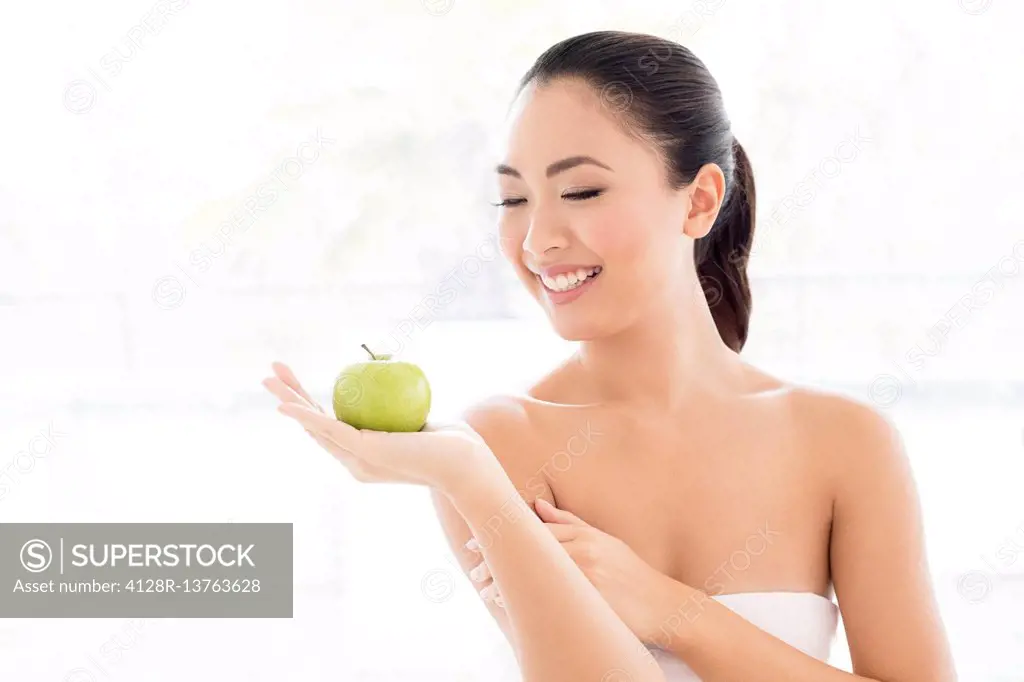 MODEL RELEASED. Young Asian woman holding apple, portrait.